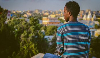 a man sitting on a ledge overlooking a city