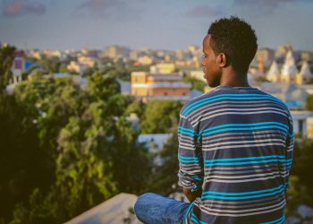 a man sitting on a ledge overlooking a city