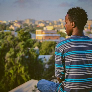 a man sitting on a ledge overlooking a city